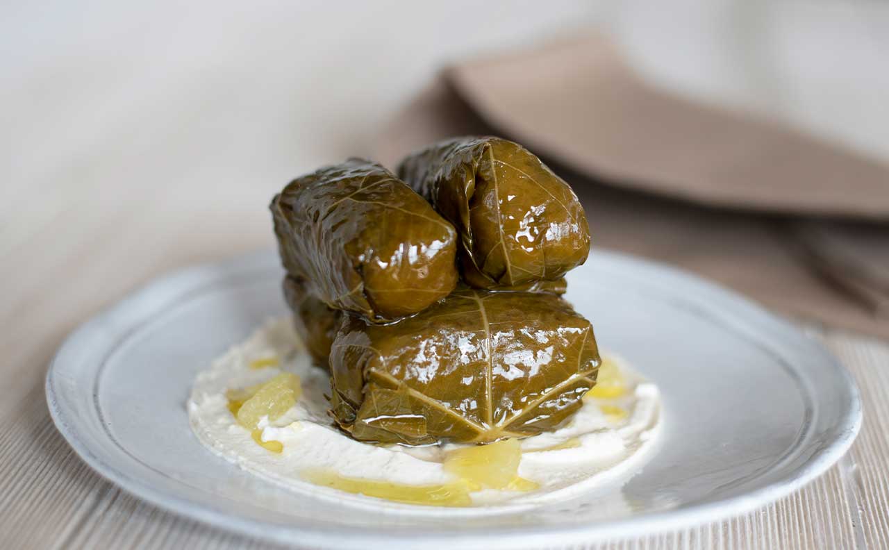 Stuffed grape leaves on a white plate from Kyma
